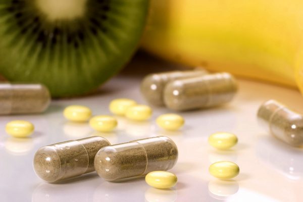 Closeup of medial piils in focus and fruits in background out of focus. Shallow DOF. Image suited for health topics about choise between medicine and healthy food